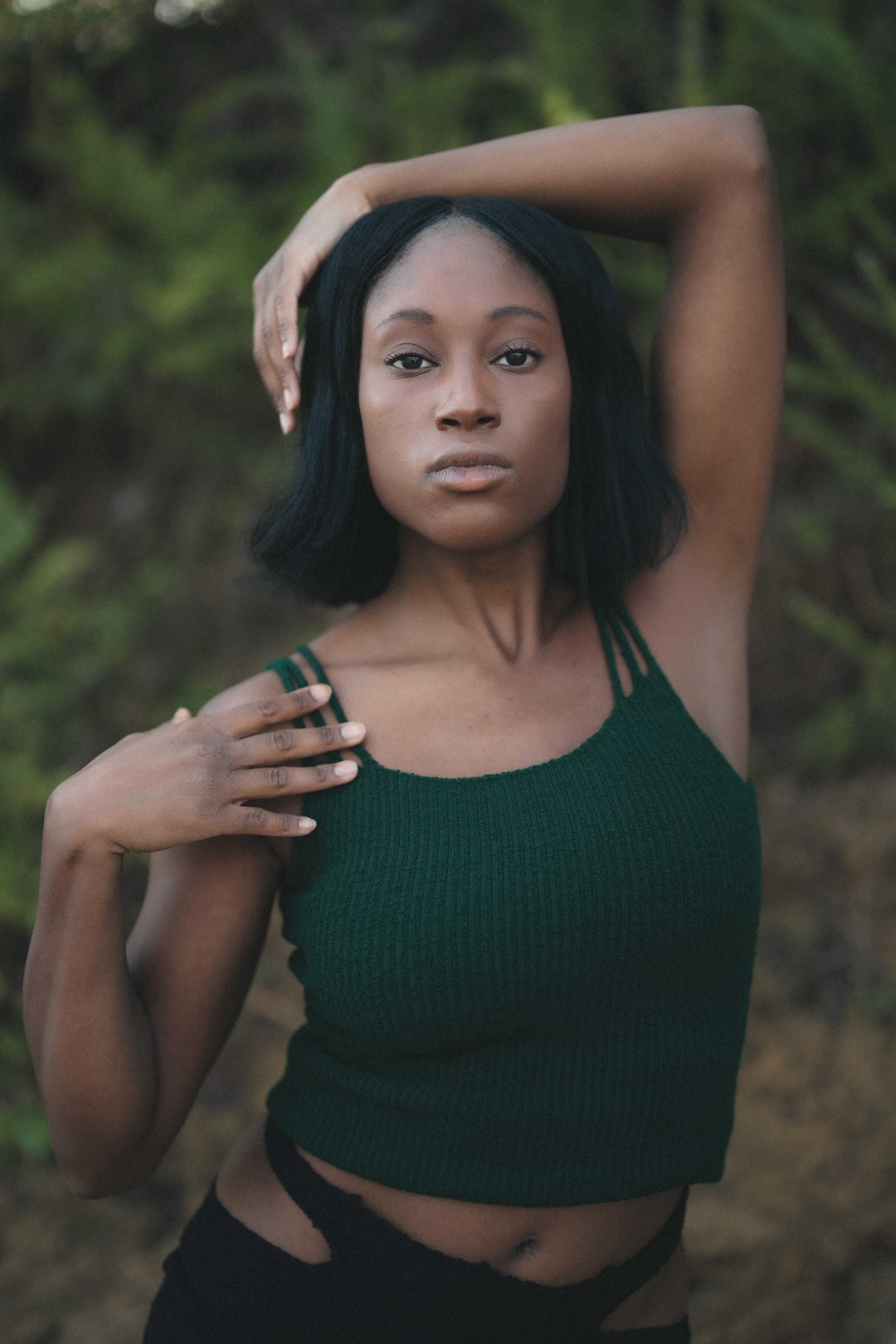 Woman in a green knit top with a blurred natural background