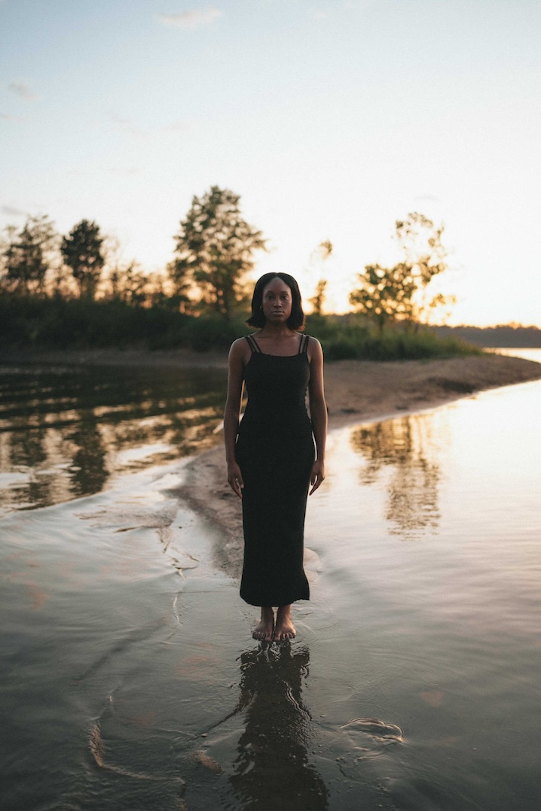 woman standing in shallow water in all black knit outfit 