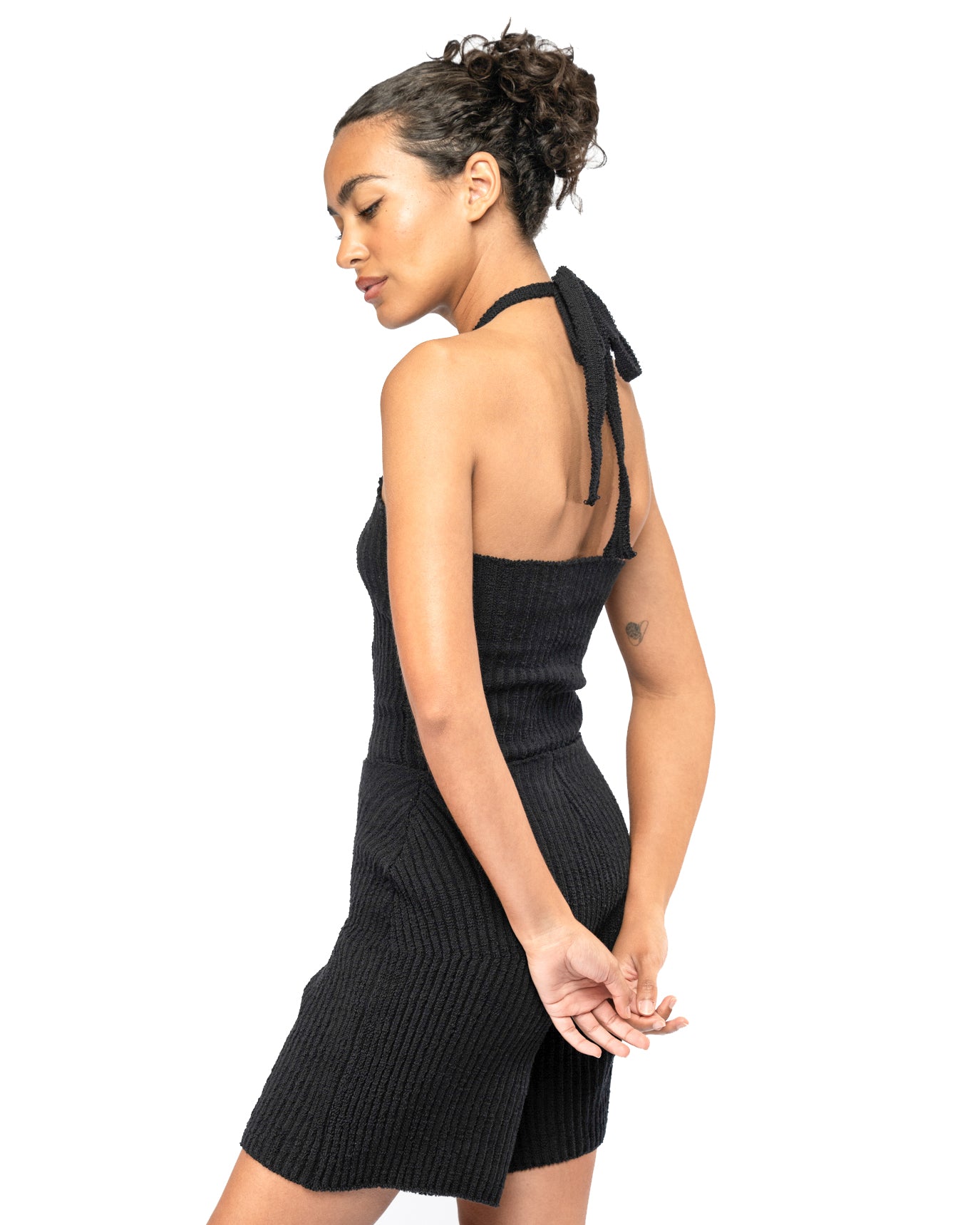 Woman wearing a black halter top and knit shorts on a white background