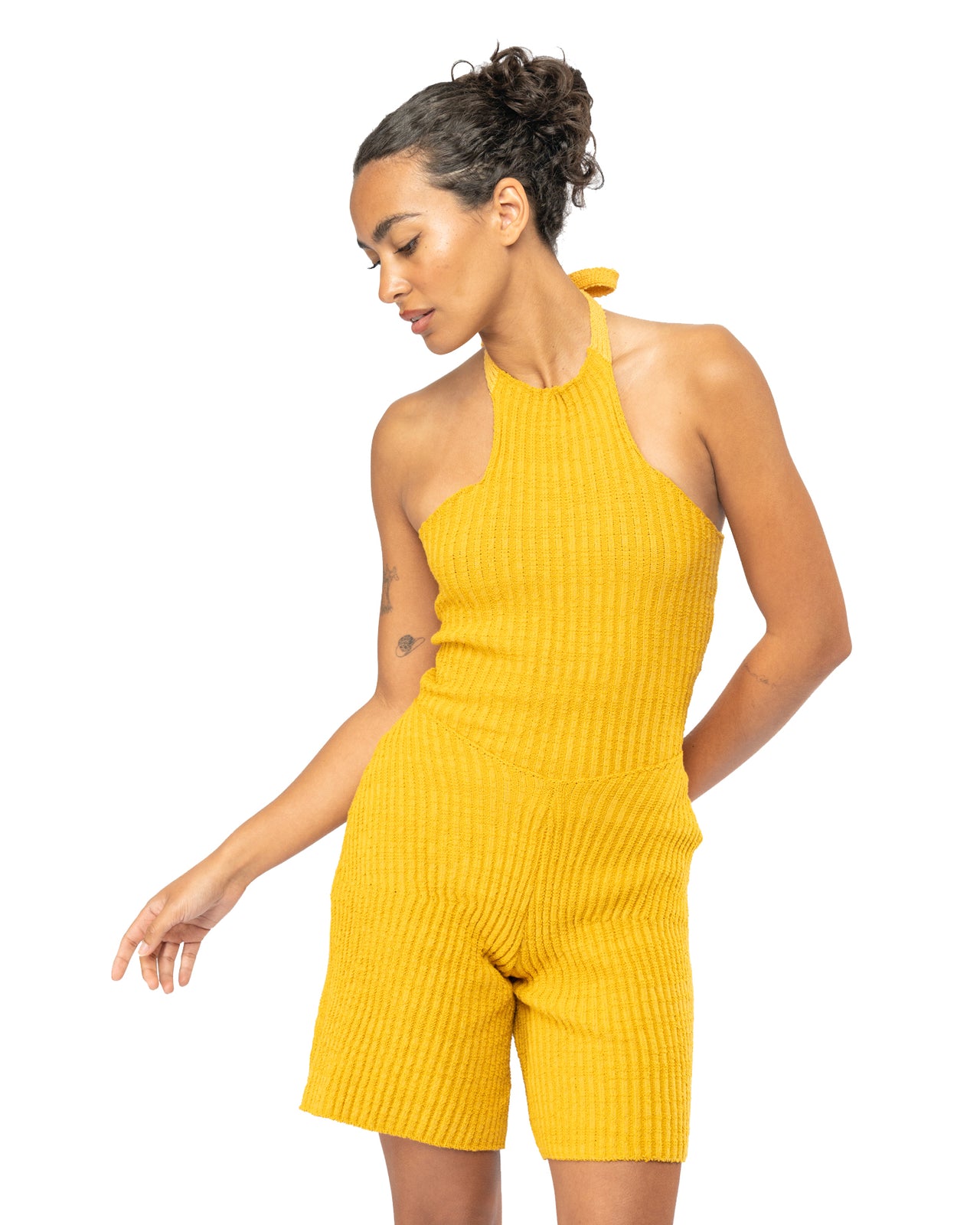 Woman wearing a yellow ribbed knit set on a white background