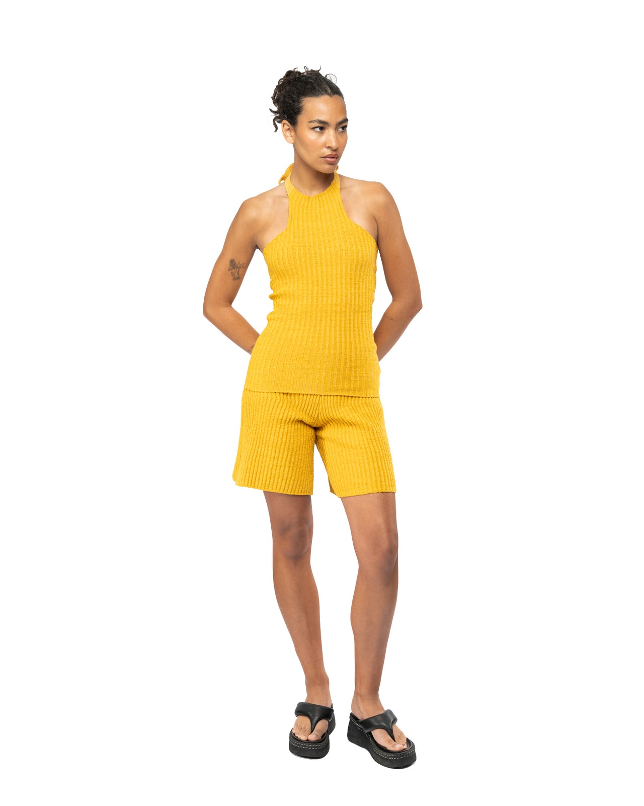 Woman wearing a yellow ribbed outfit on a white background