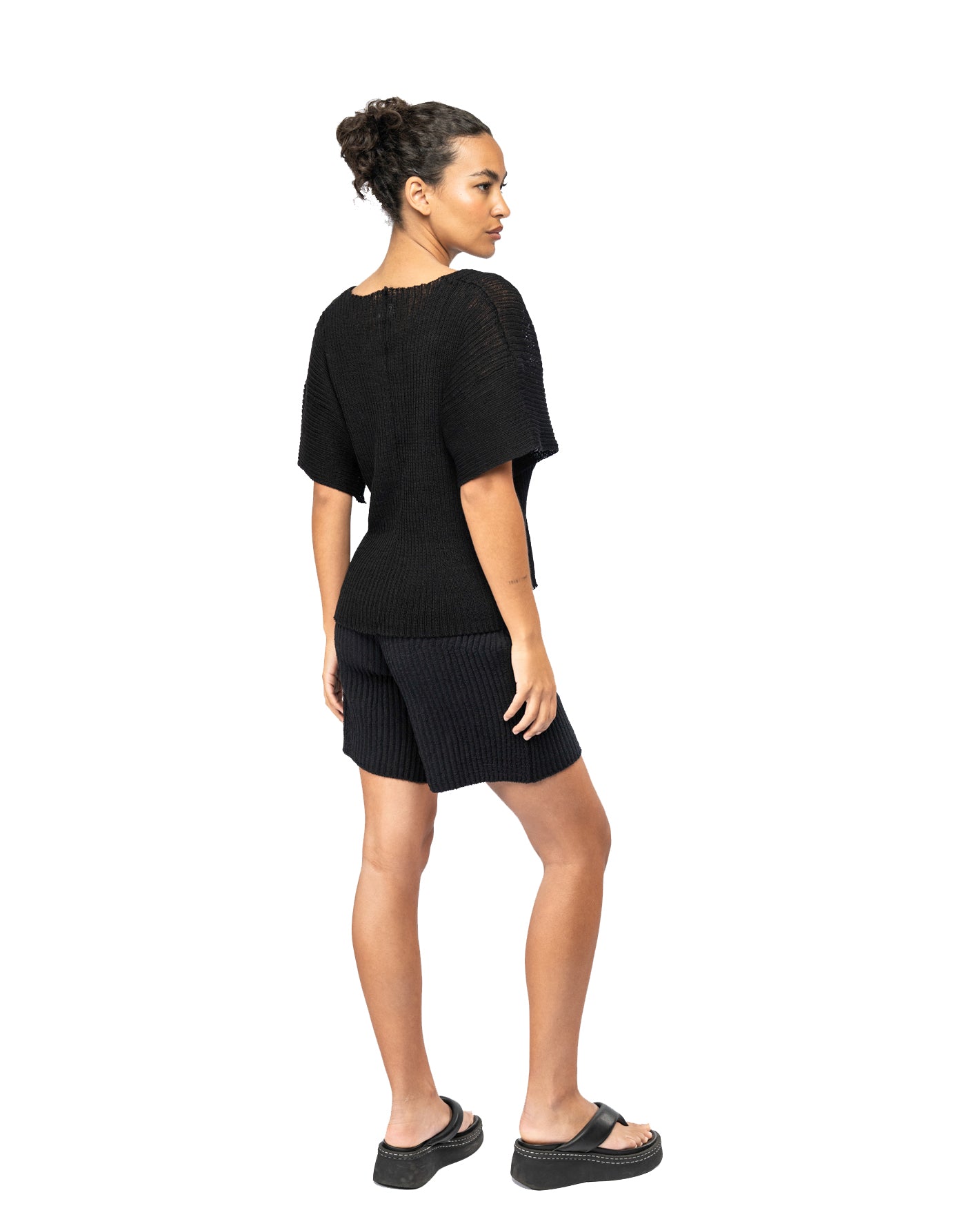 Woman wearing a black knit outfit on a white background