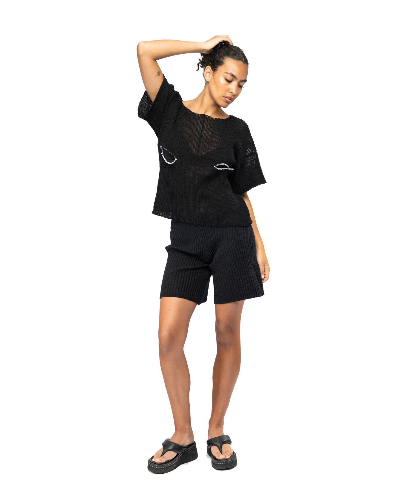 Person wearing a black knit outfit with a white background