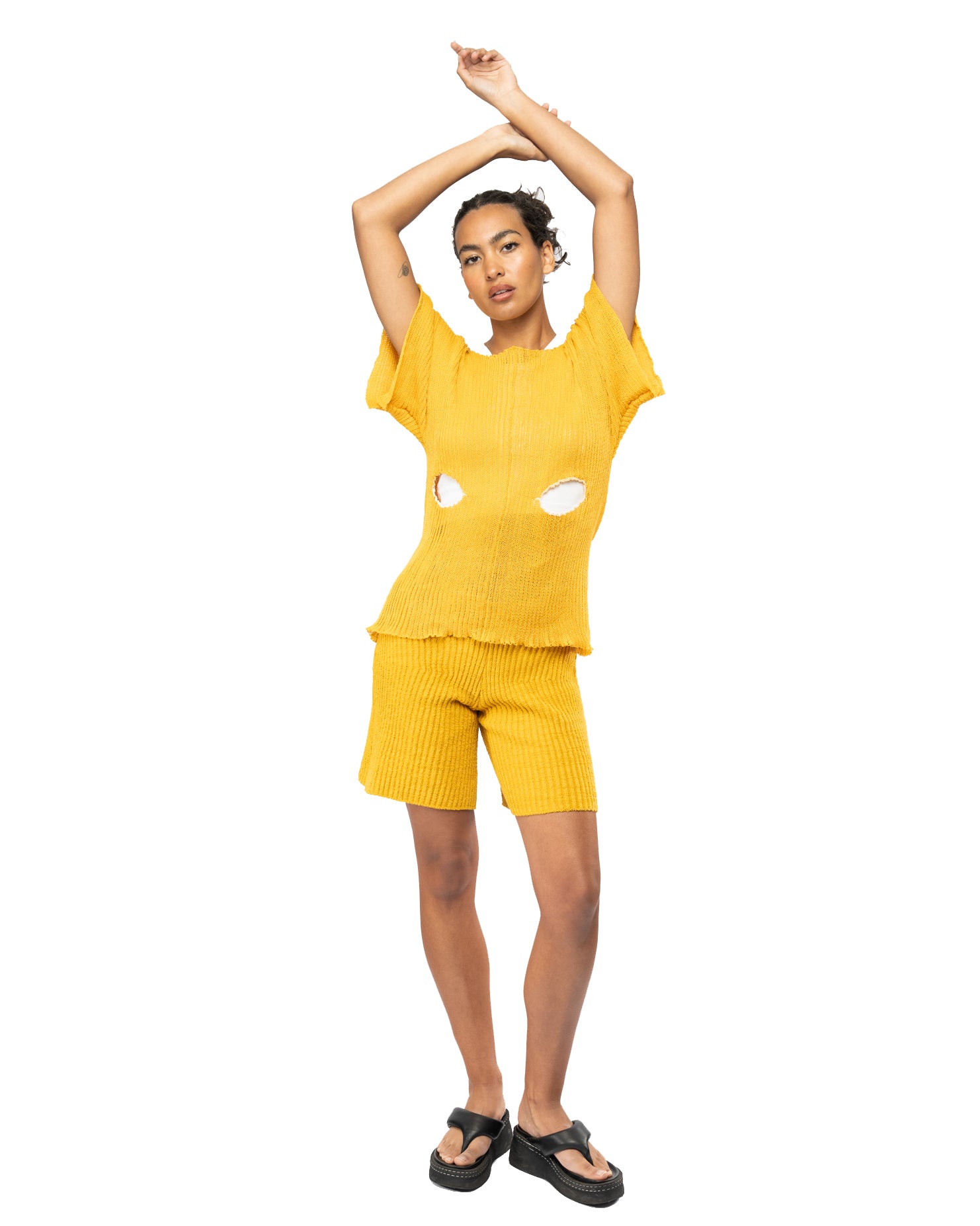 Person wearing a yellow knit outfit with cut-out design on a white background