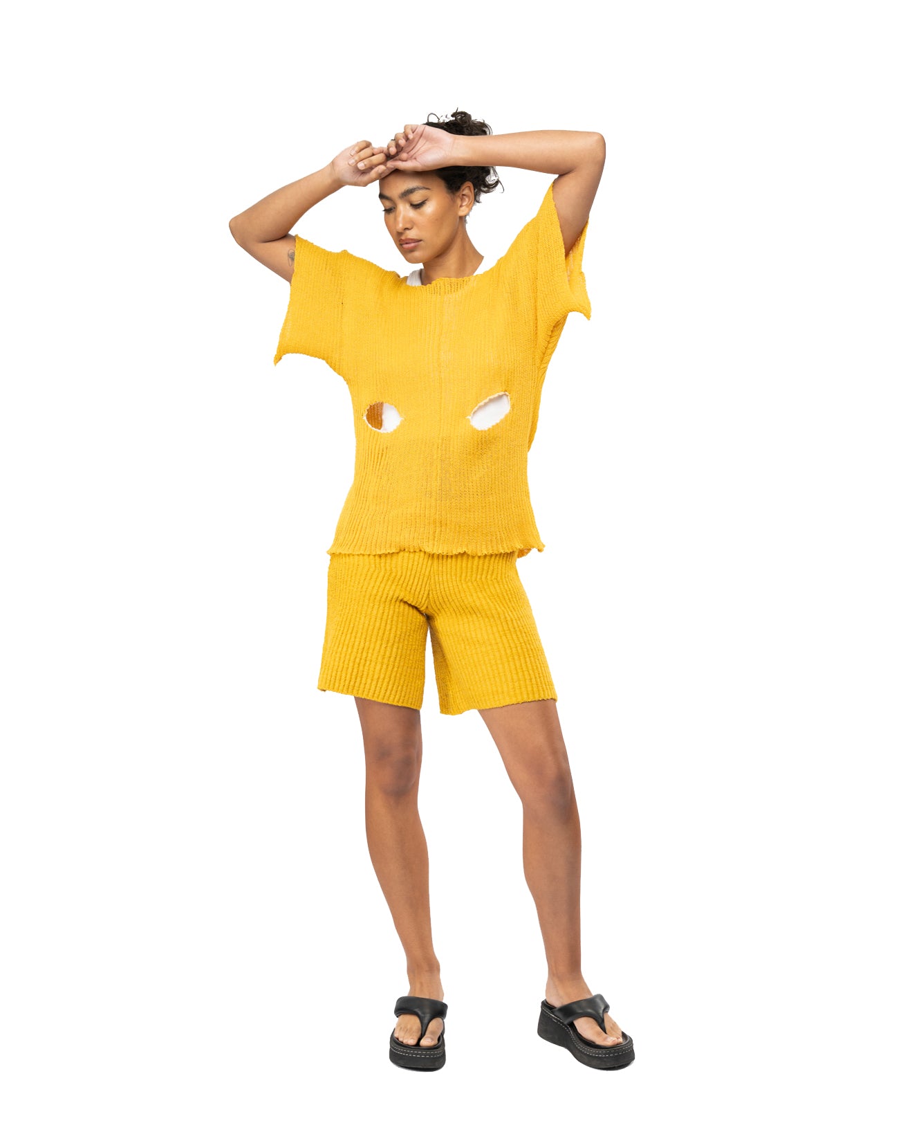 Person wearing a yellow knit outfit with cut-out design on a white background
