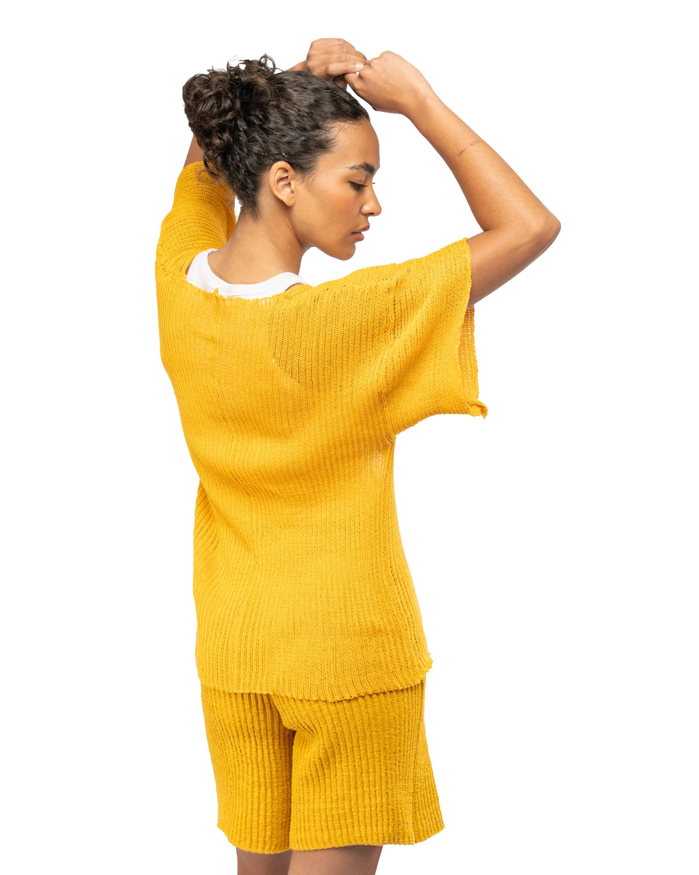 Woman wearing a yellow knit outfit on a white background